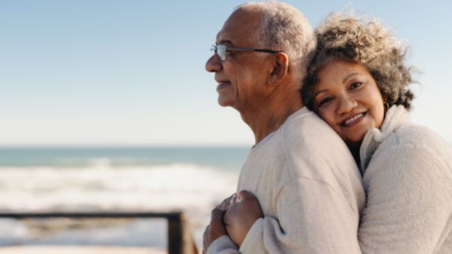 Älteres Paar umarmt sich am Strand, Symbolbild für Demenz und Pflege